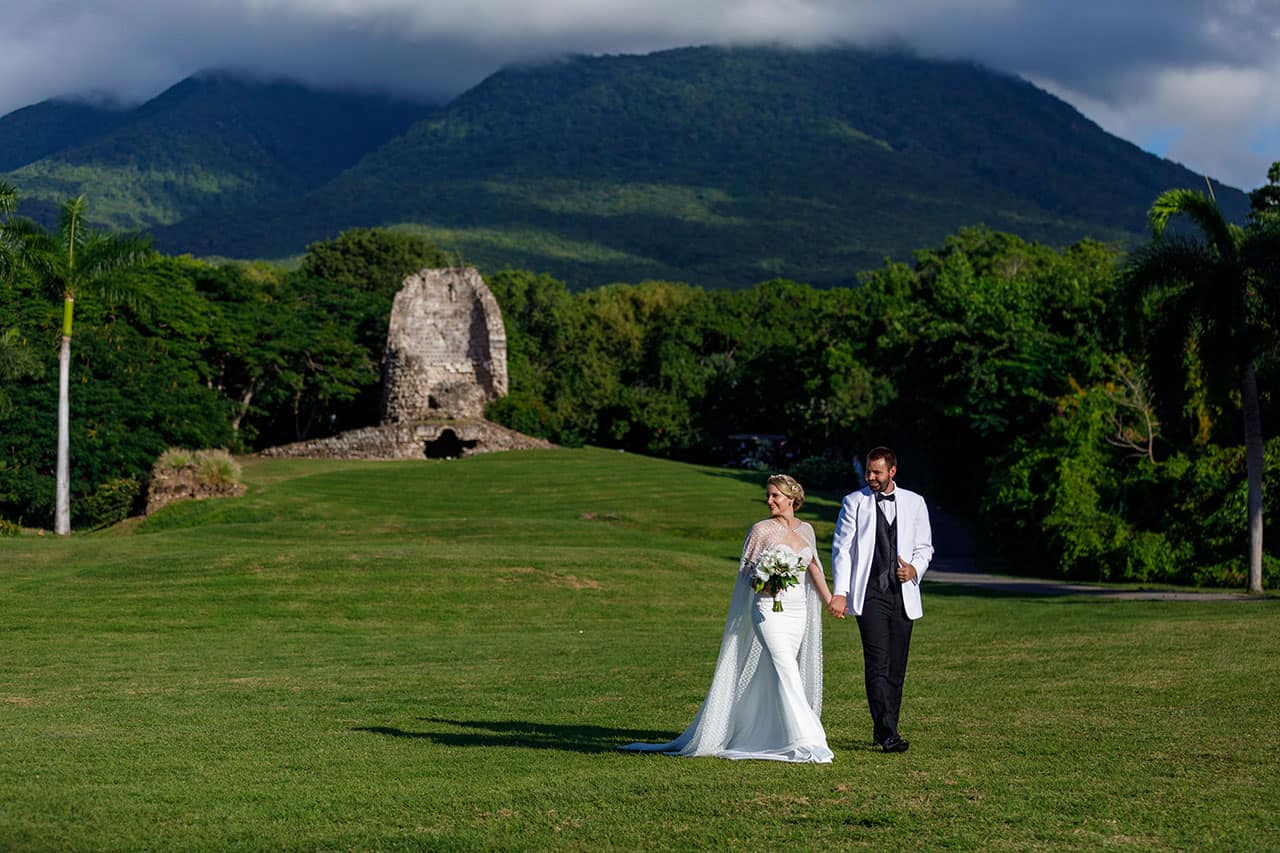 Wedding couple walking on the golf course with Nevis Peak and some ruins in the background